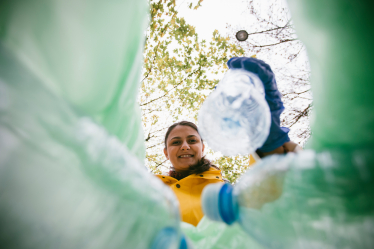 Woman recycling plastic bottles into bin